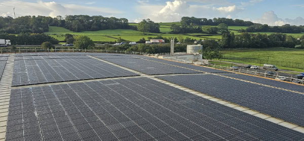 Large rooftop solar panel installation on a commercial building, generating renewable energy against a scenic countryside backdrop. ARC Renewables delivers high-efficiency solar solutions for businesses across the UK.